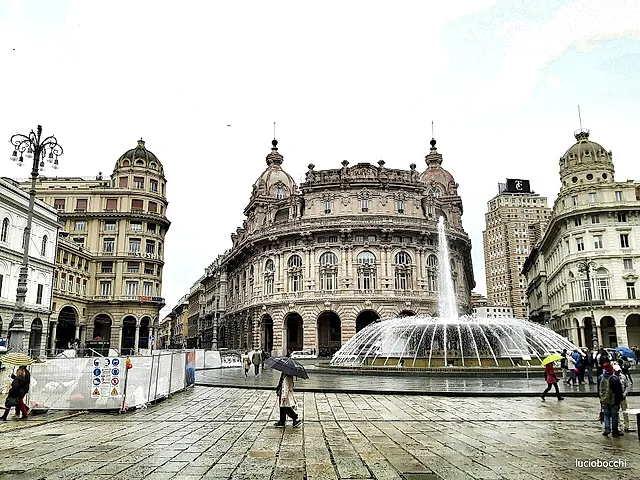 Piazza De Ferrari in Genoa: the large fountain in front of the grand palaces on a rainy day
