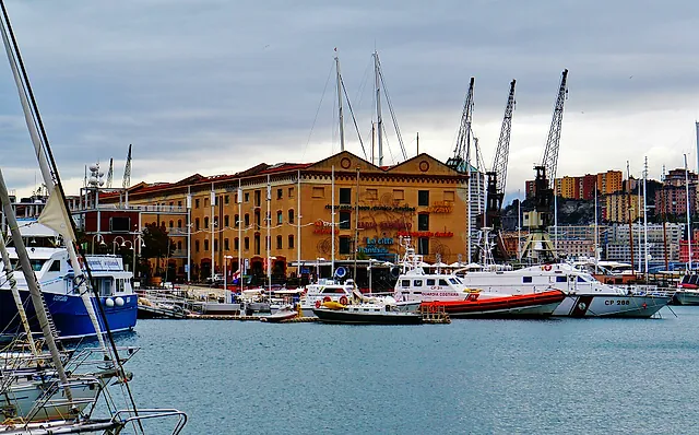 Fishing and rescue boats along the quay of the Porto Antico, with the old warehouse buildings and port cranes behind